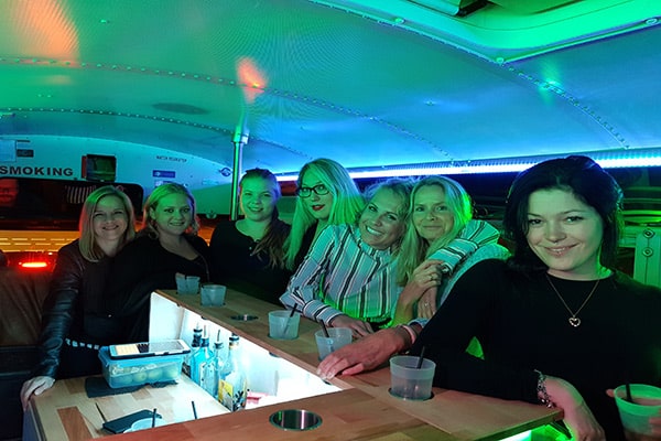 Sieben Frauen an der Partybus Bar lachen bei grünem Partylicht