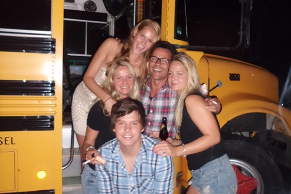 Fünf köpfige Familie vor einem gelben US Schoolbus Partybus lacht