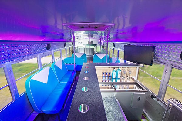 Partybus Innenraum mit Lila licht und türkisen Möbeln mit Bar und Getränken