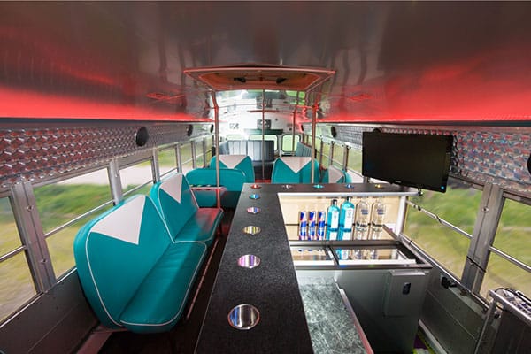 Partybus Innenraum mit Bar, türkisen Möbeln und rotem Partylicht