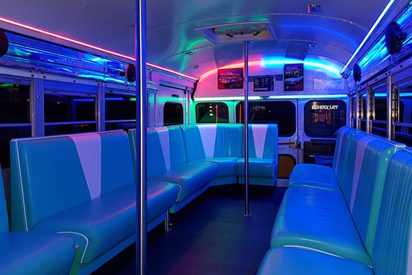 Partybus Innenraum mit Diner Möbeln, Poledance Stangen und Partylicht in rot und blau