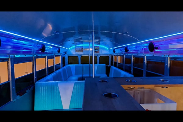 Partybus Innenraum blau mit Diner Möbeln, Poledance Stangen und Partylicht